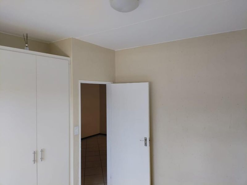 A simple, empty bedroom featuring a built-in wardrobe and neutral wall finishes, offering a blank canvas for personalization.