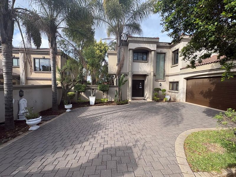 Front elevation of a double-story residence featuring a paved driveway, integrated double garage, and established garden landscaping.