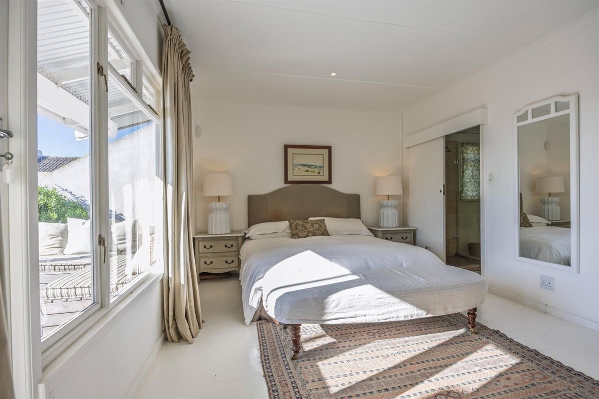 Bright and airy bedroom featuring large windows, neutral finishes, and direct access to an en-suite bathroom.
