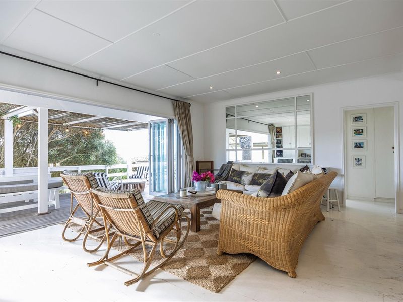 Bright open-plan living area featuring a panelled ceiling, recessed lighting, and large bi-fold doors opening onto an expansive timber deck.