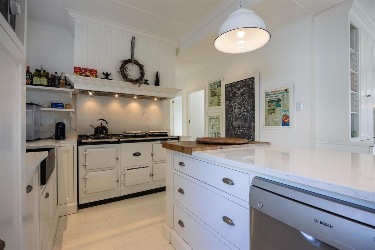 A bright, well-maintained kitchen featuring a classic range oven, stone-topped island, and ample built-in cabinetry with a clean, modern aesthetic.