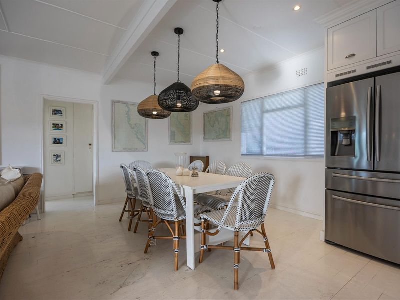Bright open-plan dining area featuring painted timber floors, recessed lighting, and built-in cabinetry, creating a clean and functional living space.
