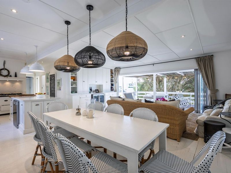 Spacious open-plan living and dining area featuring a modern kitchen with island, integrated cabinetry, and seamless flow to an outdoor patio through sliding doors.