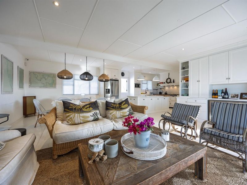 Spacious open-plan living and kitchen area featuring white cabinetry, a central island, recessed lighting, and light timber flooring throughout.