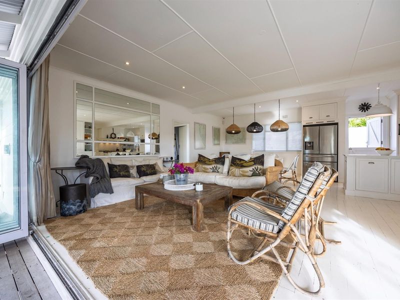 Bright open-plan living and kitchen area featuring a panelled ceiling, recessed lighting, and seamless flow to the outdoor patio through large sliding glass doors.