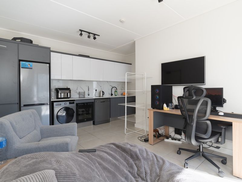 Modern open-plan living area featuring a contemporary kitchen with sleek cabinetry, marble-look splashback, and integrated appliances, seamlessly connected to a functional living and workspace.