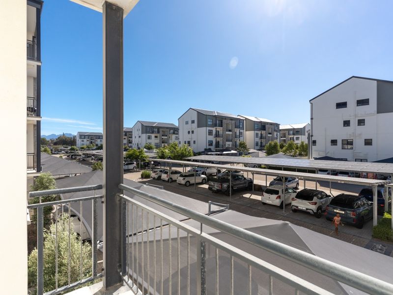 Elevated view from a balcony overlooking a residential apartment complex with covered parking bays and paved driveways.
