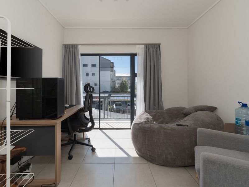 A bright bedroom featuring tiled flooring and a sliding glass door that opens onto a private balcony.