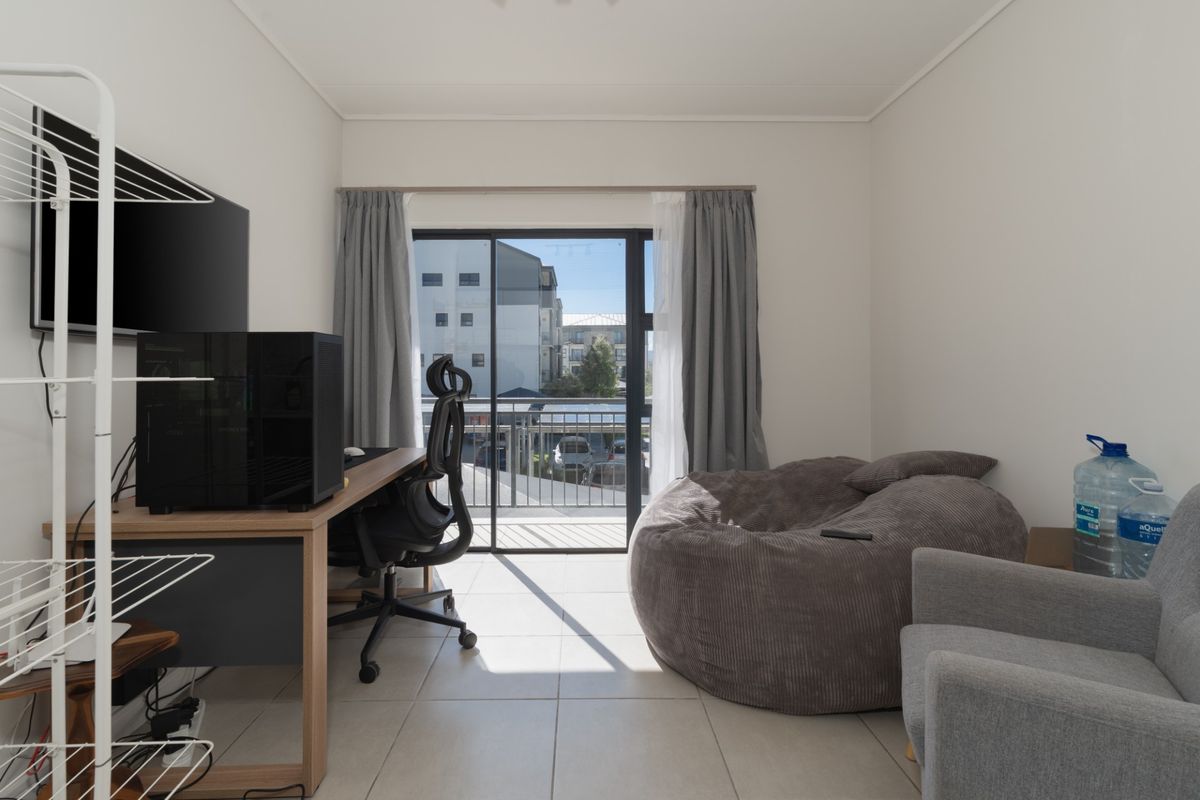 A bright bedroom featuring tiled flooring and a sliding glass door that opens onto a private balcony.