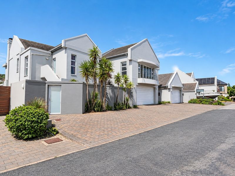 Front elevation of a modern residential property featuring a paved driveway, double garage, and balcony, showcasing well-maintained exterior finishes.