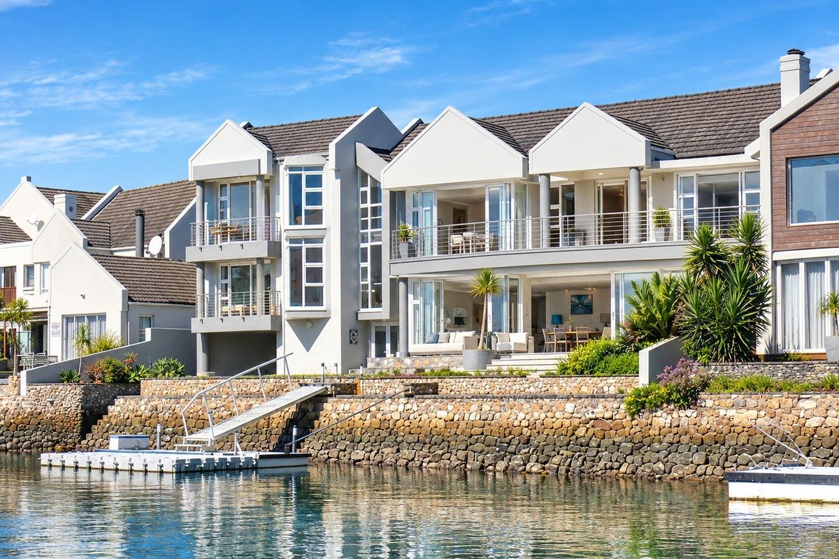A stunning waterfront property featuring multi-level balconies, a private jetty, and direct water access, showcasing modern architectural design and well-maintained exterior finishes.