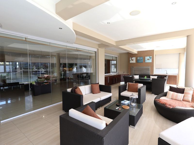 Spacious covered patio featuring large glass sliding doors, tiled flooring, recessed lighting, and a built-in braai area, perfect for indoor-outdoor entertaining.