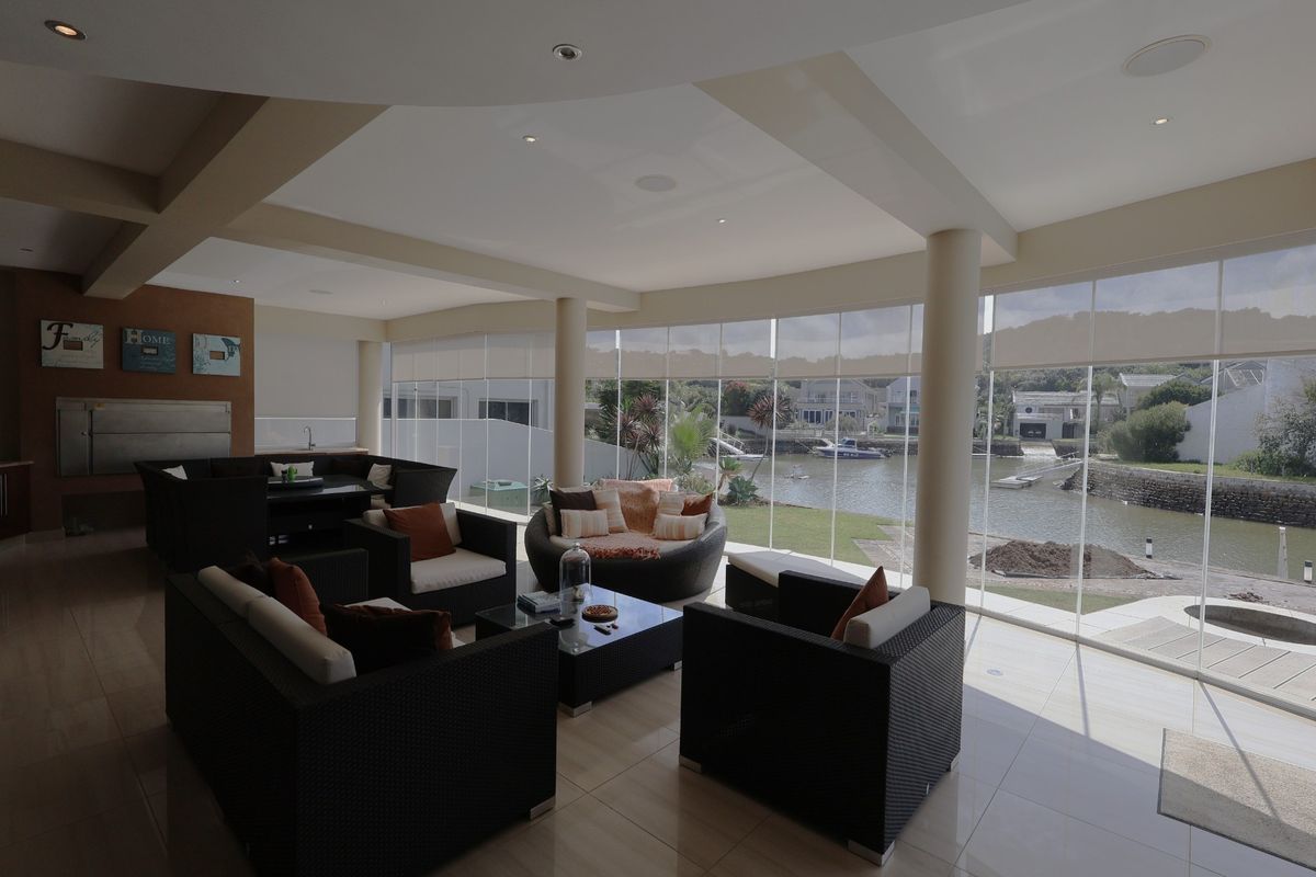 Spacious living area featuring floor-to-ceiling glass walls with scenic water views, tiled flooring, recessed lighting, and a built-in fireplace.