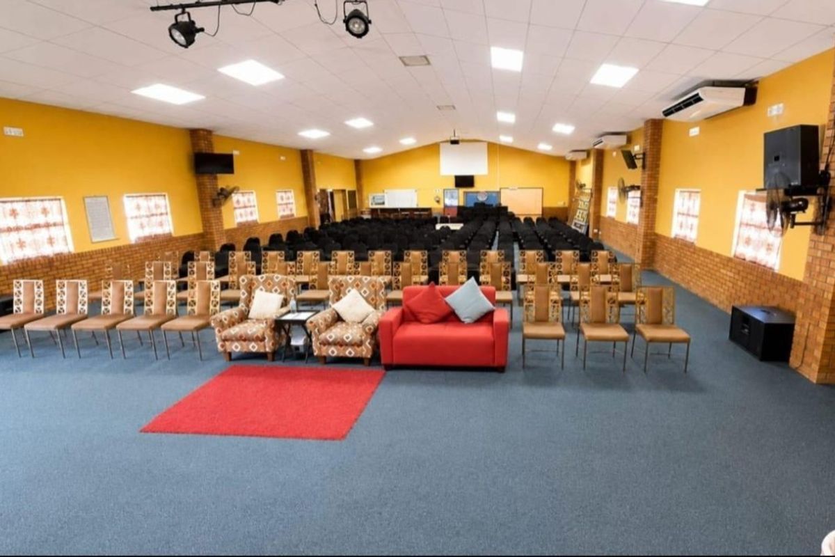 Spacious commercial hall featuring exposed brick accents, suspended ceiling with recessed lighting, and wall-mounted air conditioning, suitable for events or community gatherings.