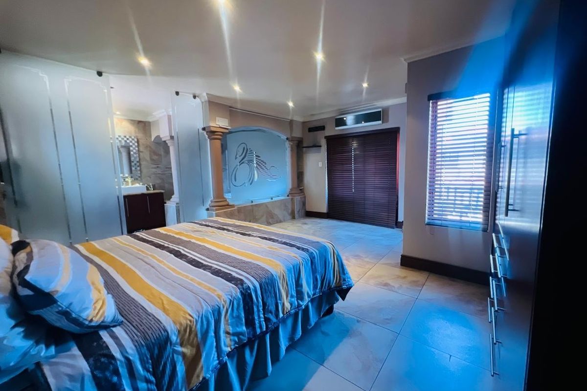 Spacious bedroom featuring tiled flooring, recessed lighting, air conditioning, and an integrated en-suite bathroom area with decorative architectural columns.