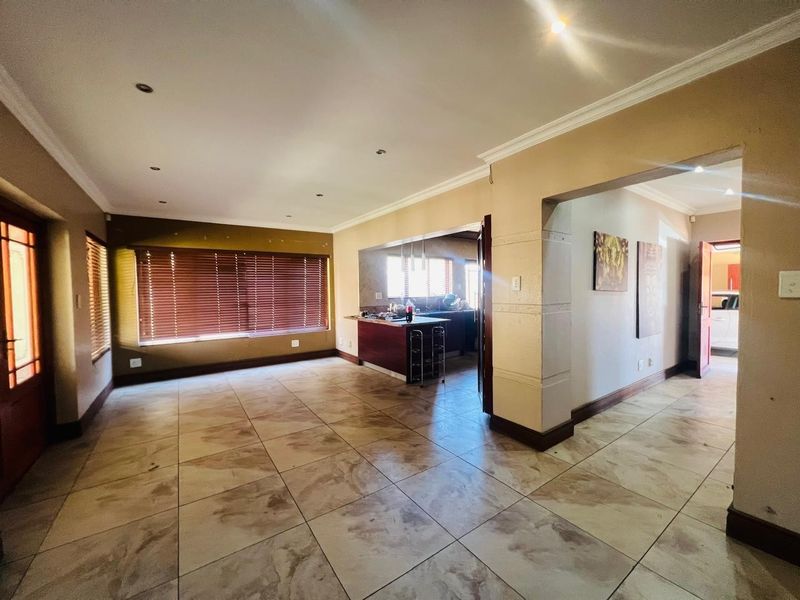 Spacious open-plan living area featuring tiled flooring, recessed lighting, and a breakfast counter connecting to the kitchen space.