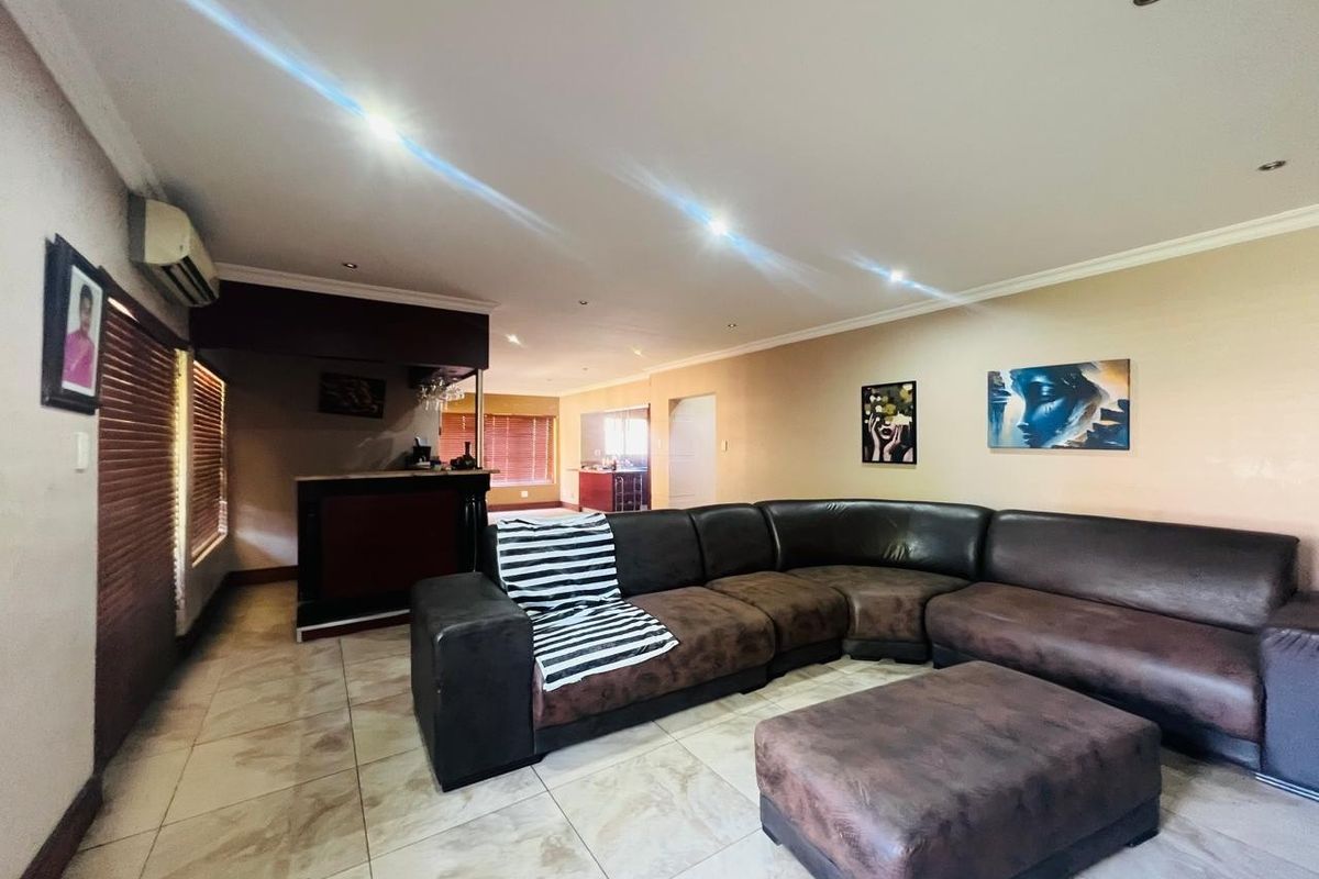 Spacious living area featuring tiled flooring, recessed lighting, and a built-in bar, offering a functional layout with integrated air conditioning.