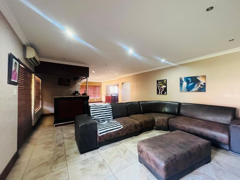 Spacious living area featuring tiled flooring, recessed lighting, and a built-in bar, offering a functional layout with integrated air conditioning.