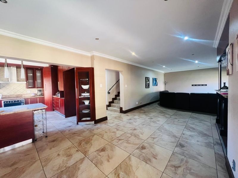 Spacious open-plan living area featuring tiled floors, recessed lighting, and a well-defined kitchen space with built-in cabinetry and an island.