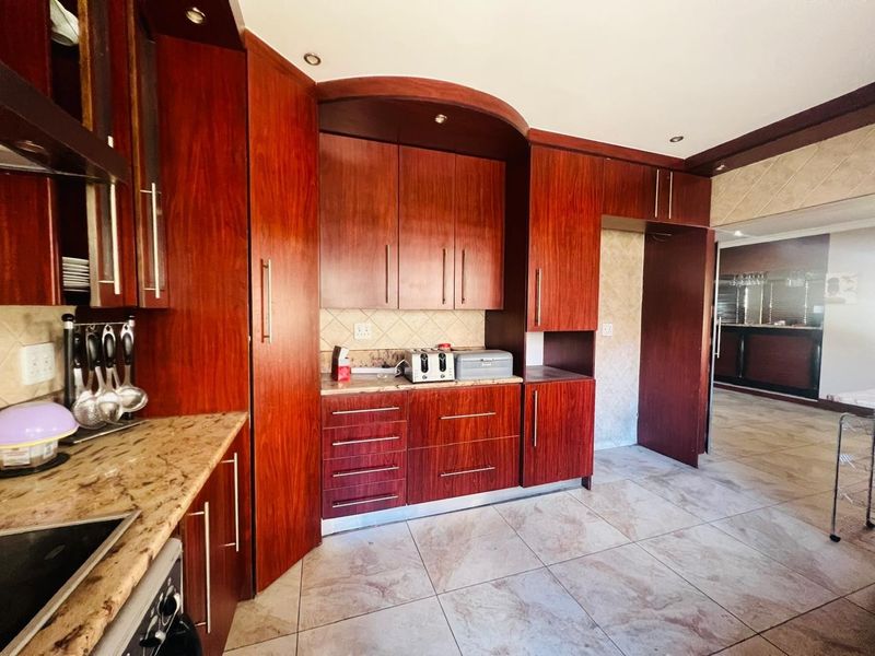 A kitchen featuring dark wood cabinetry, granite countertops, and tiled flooring, offering a functional layout with ample storage space.