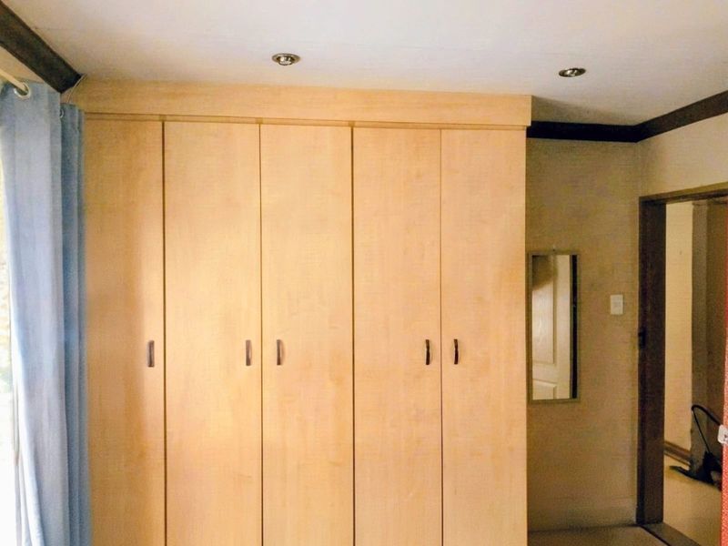 Bedroom featuring floor-to-ceiling built-in wooden cupboards and recessed ceiling lighting.