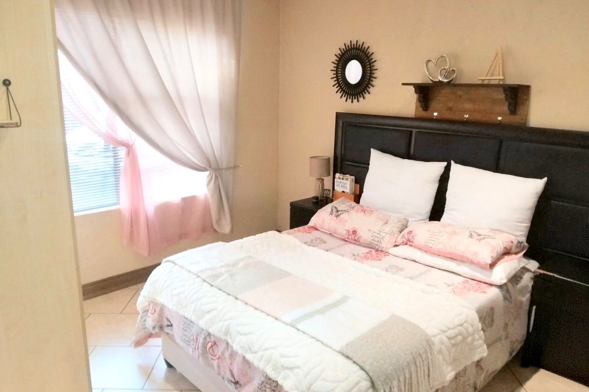 A functional bedroom featuring tiled flooring and window treatments, offering a neutral base ready for personalization.