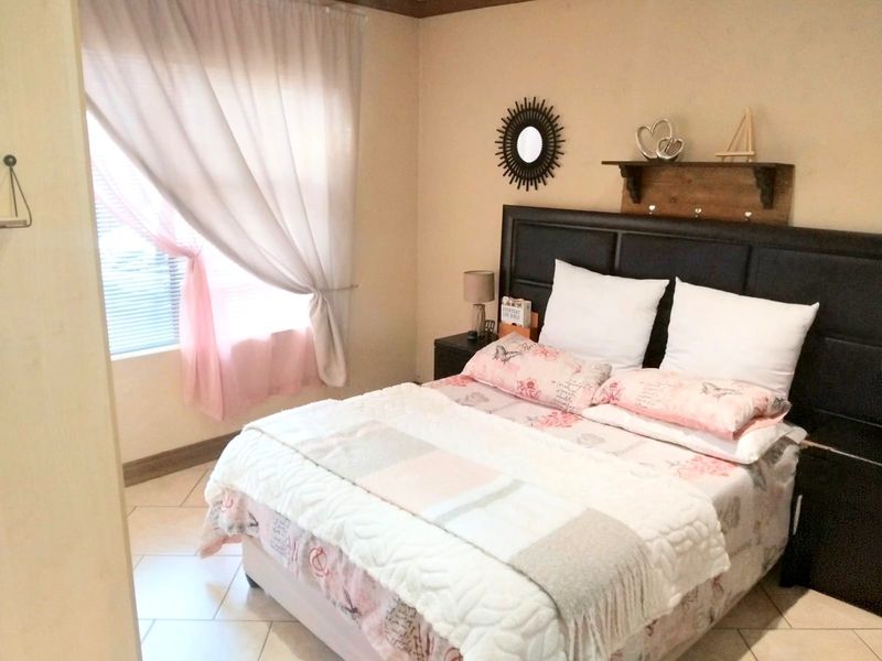 A functional bedroom featuring tiled flooring and window treatments, offering a neutral base ready for personalization.