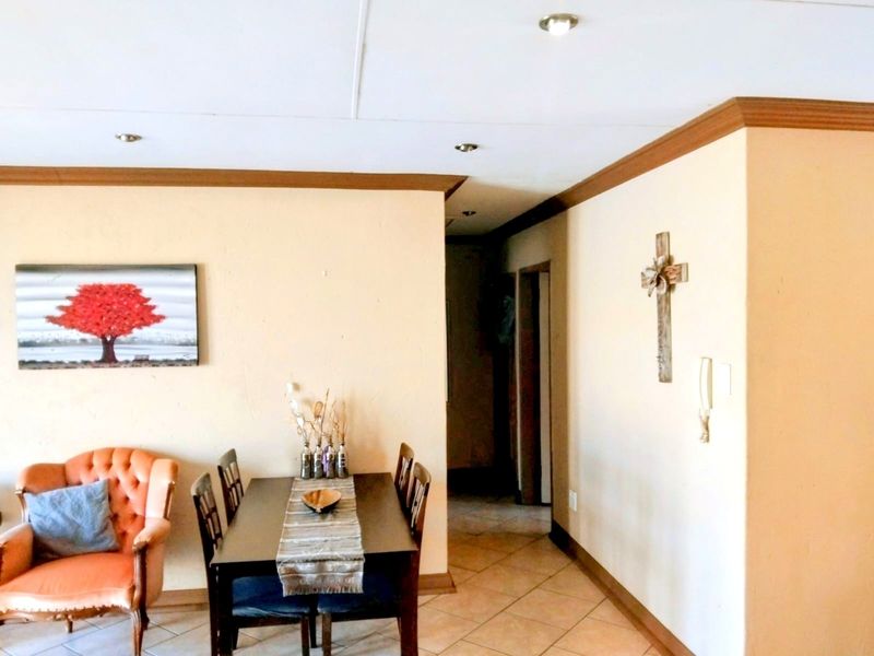 A dining area featuring tiled flooring, recessed ceiling lighting, and decorative crown molding, leading into a hallway.
