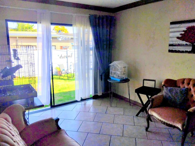 Living room featuring ceramic floor tiles, crown molding, and a large sliding glass door providing access to the rear garden area.