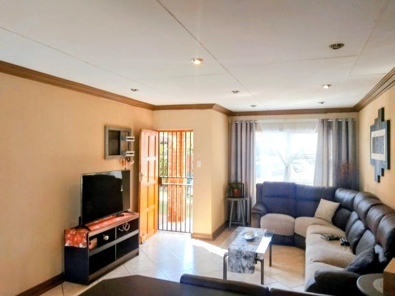 A comfortable living room featuring tiled flooring, recessed downlighting, and direct access to the exterior through a secure entrance door.