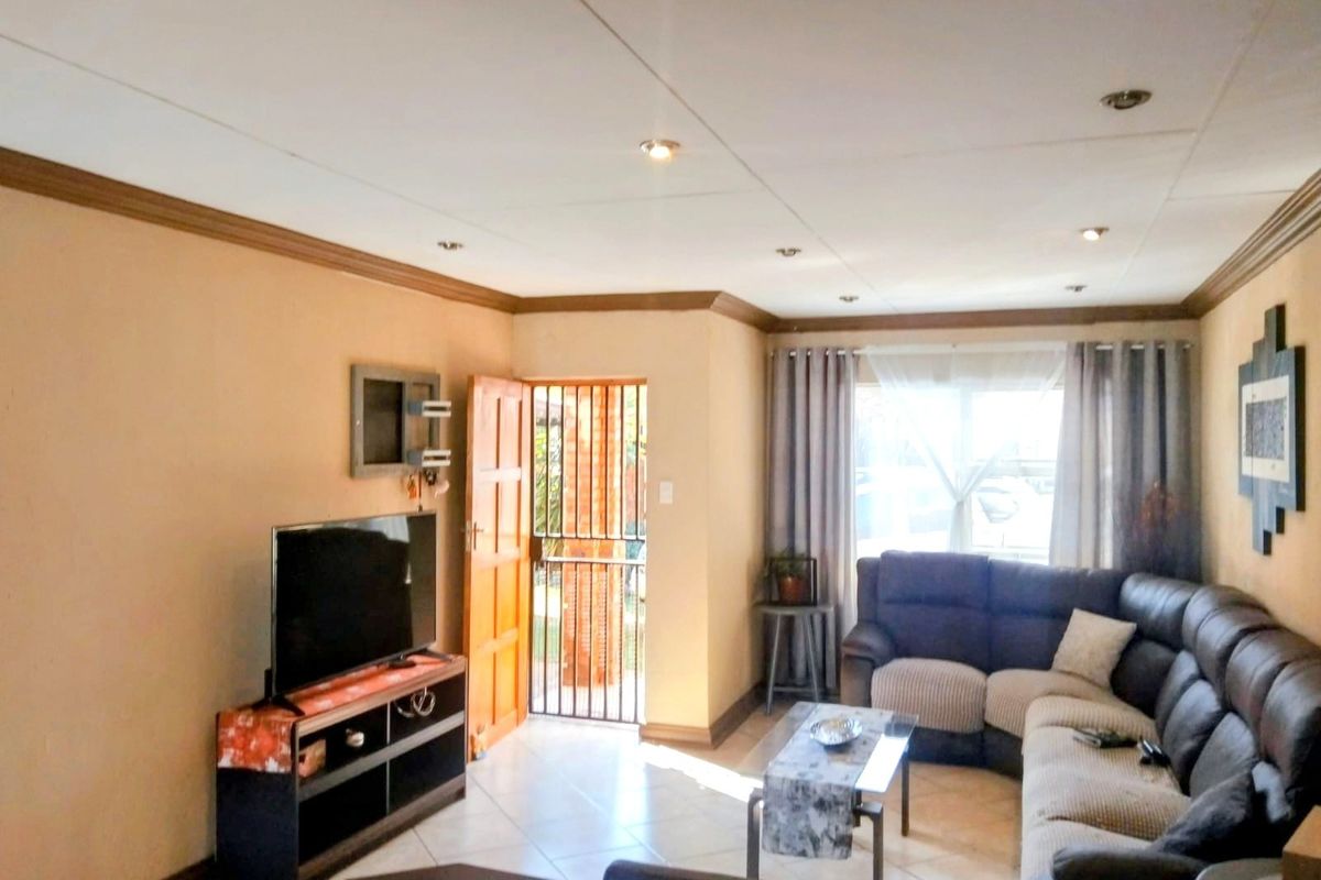 A comfortable living room featuring tiled flooring, recessed downlighting, and direct access to the exterior through a secure entrance door.