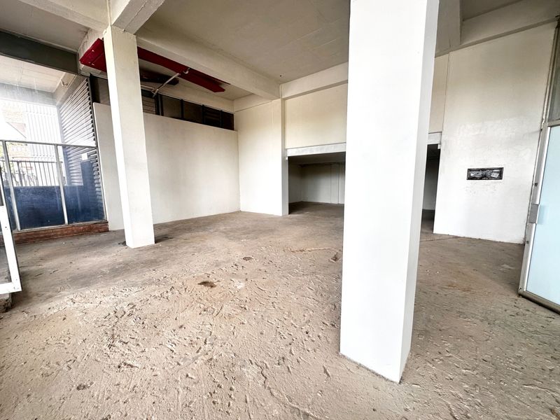 An expansive, empty commercial open-plan space featuring exposed concrete flooring, structural columns, and high ceilings, suitable for a variety of business fit-outs.