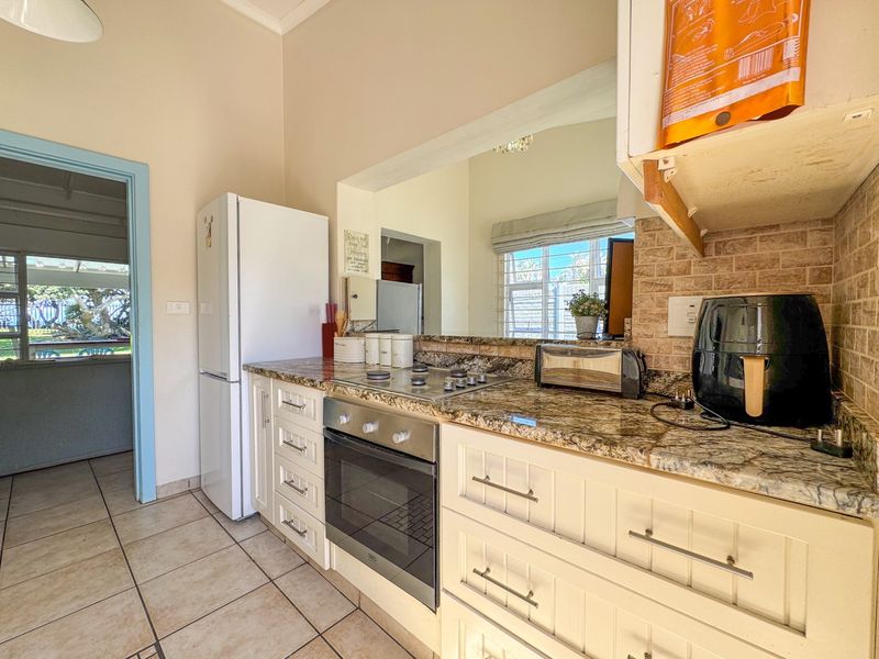 Functional kitchen featuring granite countertops, built-in oven, gas hob, and tiled backsplash with ample storage cabinetry.