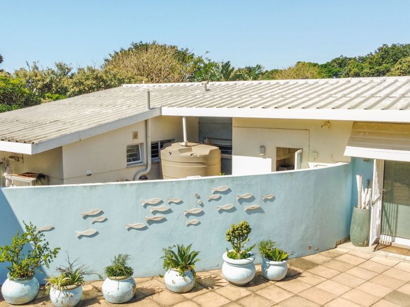 Rear exterior view of the property featuring a paved patio area, a water storage tank, and a decorative boundary wall.