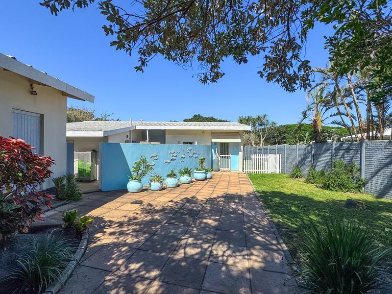 A well-maintained rear garden area featuring a paved patio, boundary wall, and established landscaping, providing a private outdoor space.
