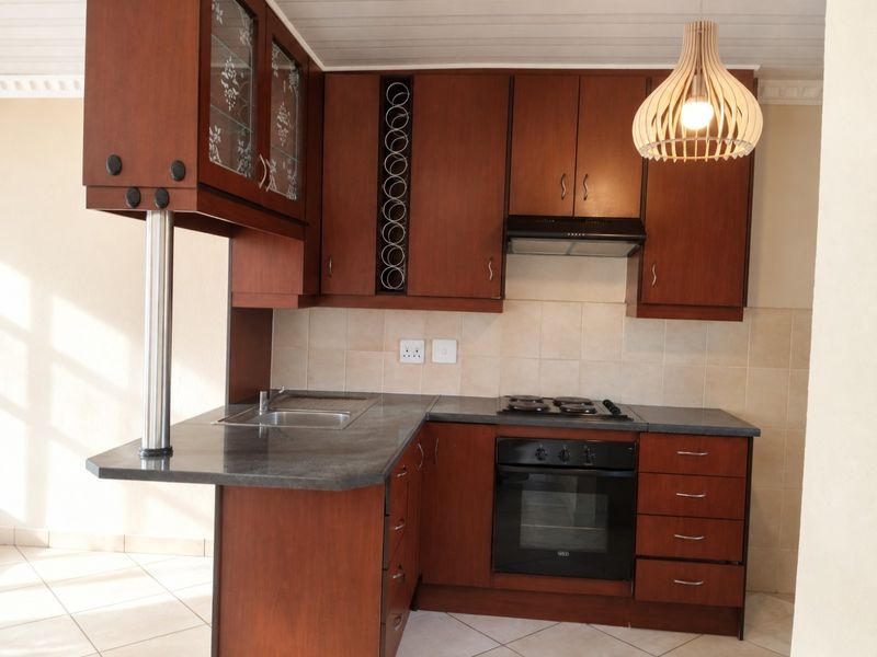 A functional kitchen featuring dark wood cabinetry, granite-look countertops, built-in oven, gas hob, and a breakfast bar extension.