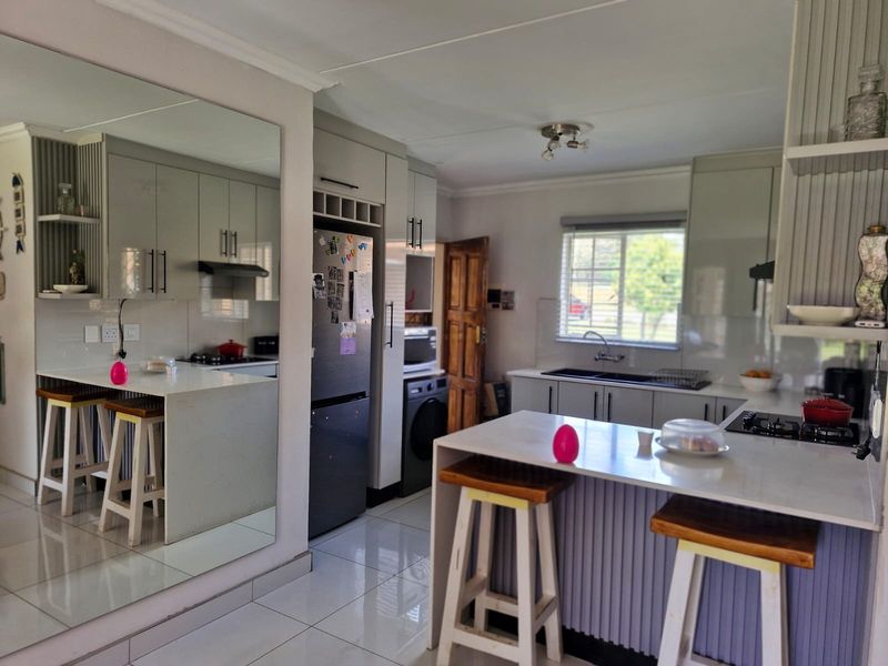 Modern kitchen featuring sleek cabinetry, stone countertops, a breakfast bar, and tiled flooring, offering a functional and well-maintained culinary space.