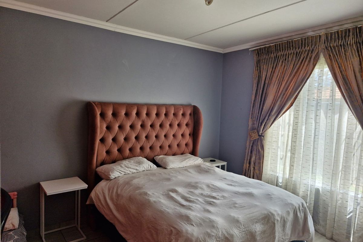 A bedroom featuring tiled flooring, neutral wall paint, and natural light provided by a window with curtain tracks.