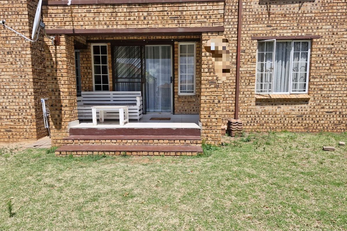 Rear view of the apartment featuring a face brick facade, a tiled patio area with sliding door access, and a small private garden space.