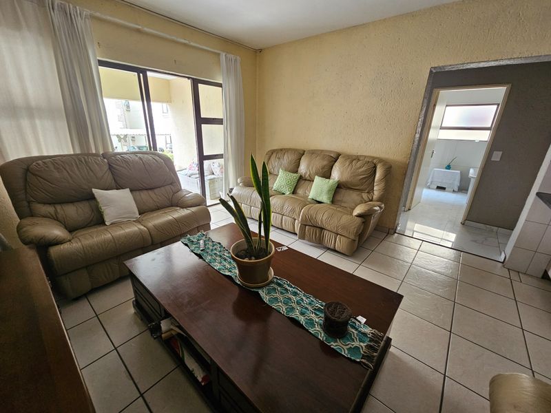A living room featuring tiled flooring and a sliding glass door leading to an outdoor area, with access to an adjacent room.