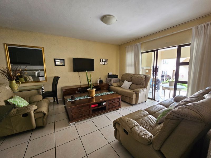 A living room featuring tiled flooring and a sliding glass door providing access to an outdoor patio area.