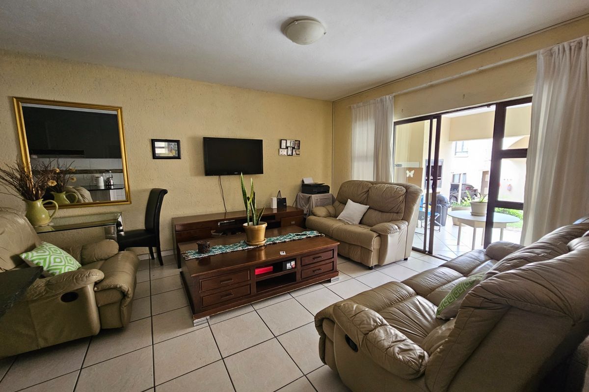 A living room featuring tiled flooring and a sliding glass door providing access to an outdoor patio area.