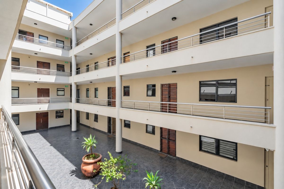 A well-maintained apartment complex courtyard featuring multi-level balconies with stainless steel railings and tiled flooring.