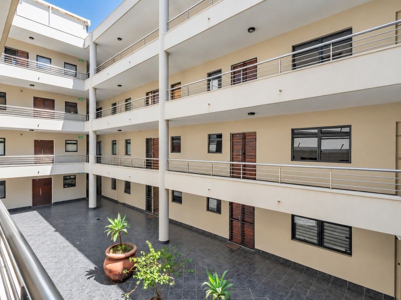 A well-maintained apartment complex courtyard featuring multi-level balconies with stainless steel railings and tiled flooring.