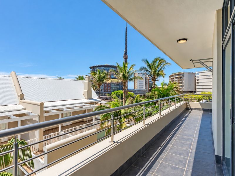 A spacious, well-maintained balcony featuring tiled flooring, a modern stainless steel balustrade, and pleasant urban views.