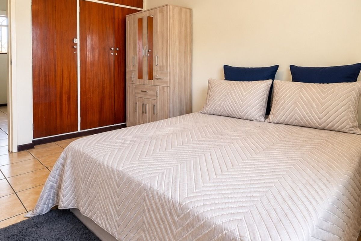 A bedroom featuring tiled flooring and built-in wooden cupboards, offering a functional and neutral space ready for personalization.