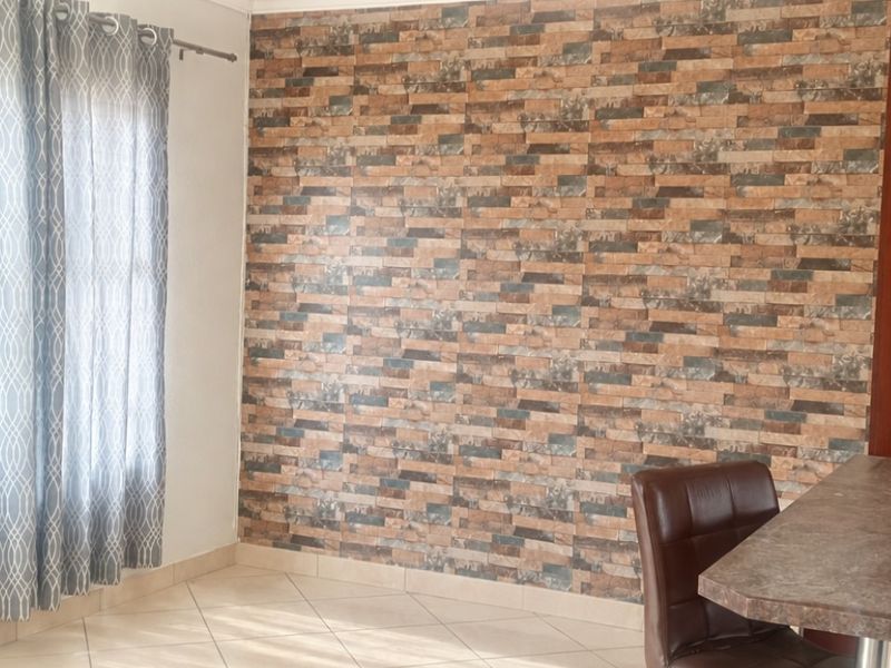 Bedroom featuring tiled flooring, a decorative stone-look feature wall, and built-in wooden cupboards.
