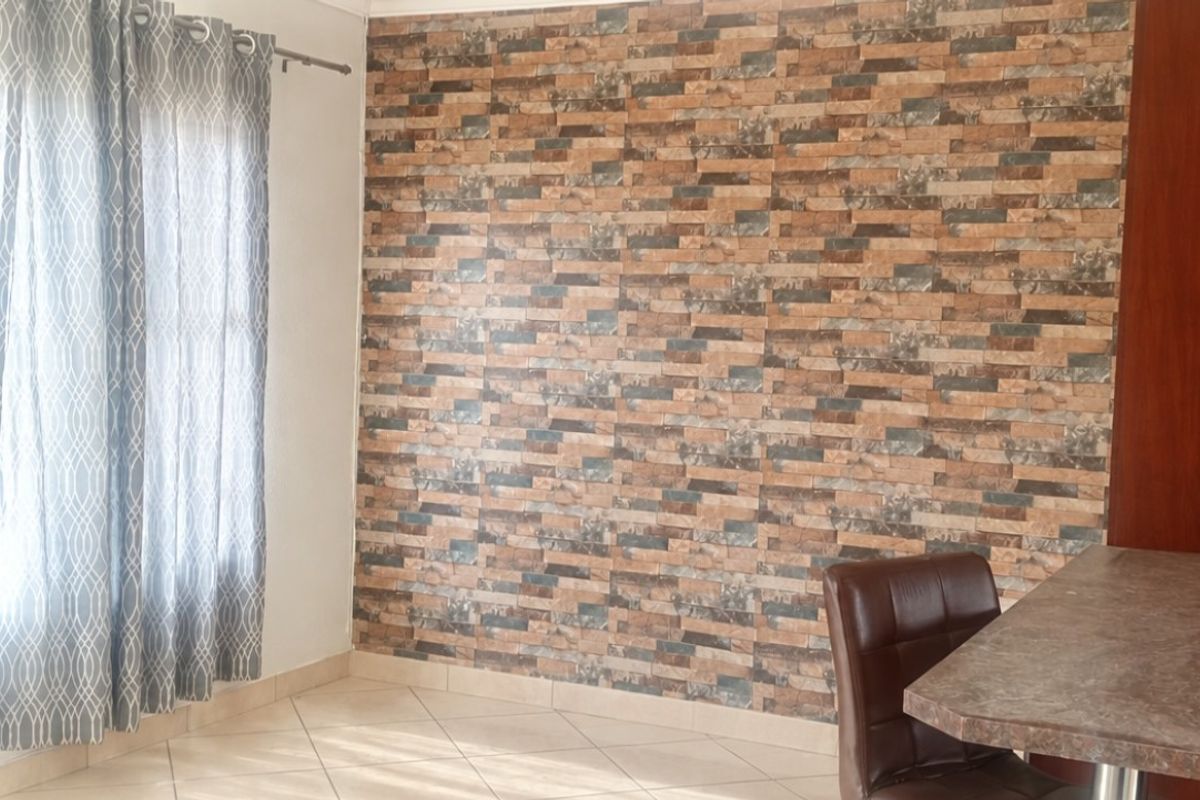 Bedroom featuring tiled flooring, a decorative stone-look feature wall, and built-in wooden cupboards.