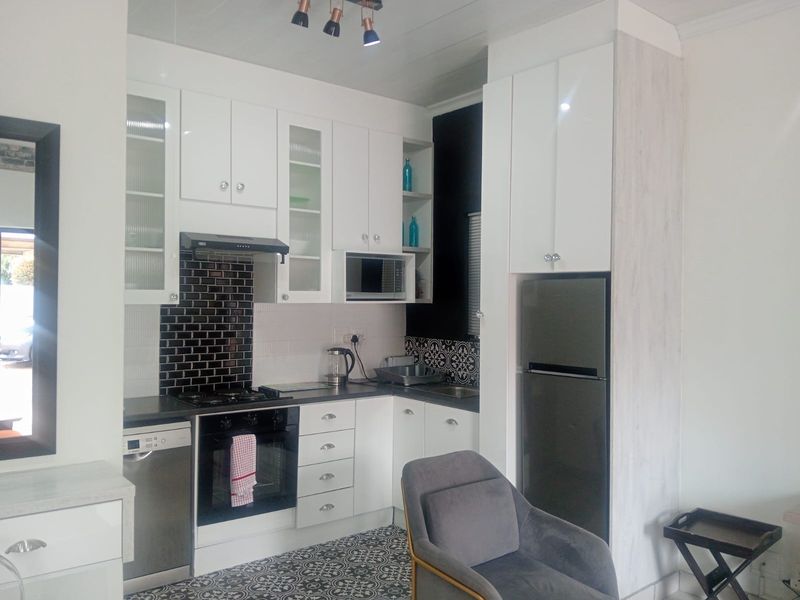 Modern kitchen featuring white cabinetry, subway tile backsplash, patterned floor tiles, and integrated appliances including a gas hob and oven.