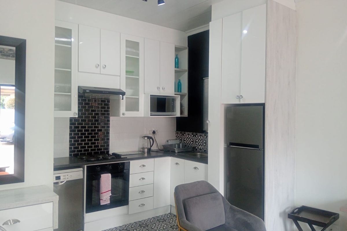Modern kitchen featuring white cabinetry, subway tile backsplash, patterned floor tiles, and integrated appliances including a gas hob and oven.